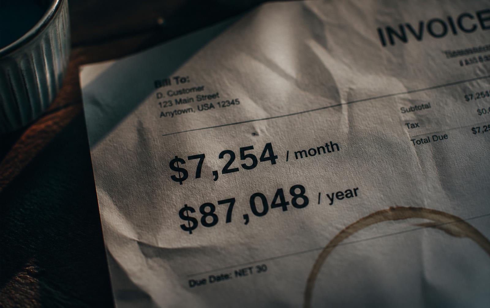 Crumpled agency invoice showing $7,254 per month and $87,048 per year